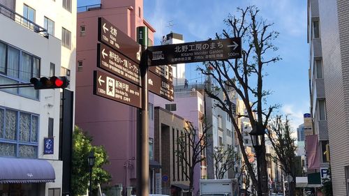 Low angle view of road sign by buildings in city