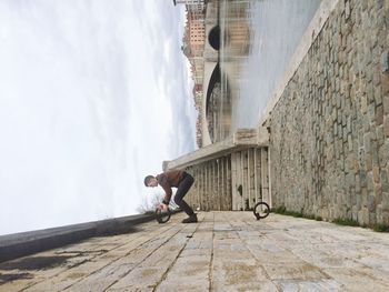 Tilt image of man climbing wall against lake