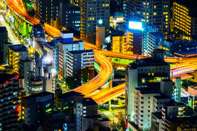 Illuminated street amidst buildings in city at night