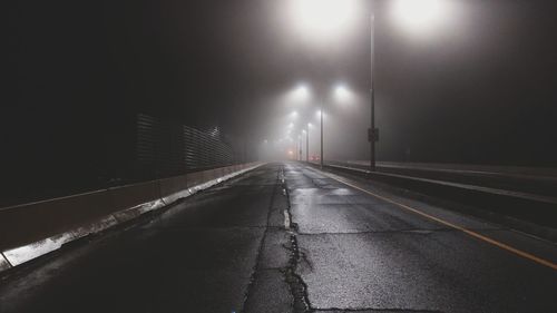Illuminated road against sky at night