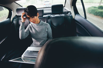 Woman using laptop in car