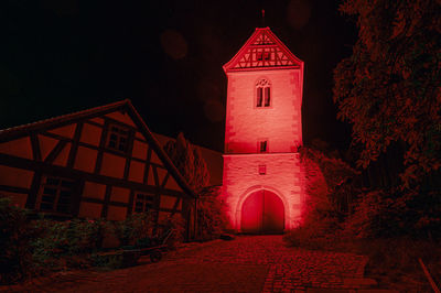 Illuminated red building against sky at night