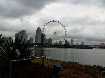 Ferris wheel in city against cloudy sky