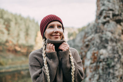 A young blonde girl walks in the autumn in the mountains with a view of the river and forest