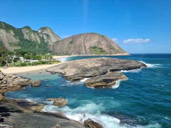 Scenic view of rocks on beach against blue sky