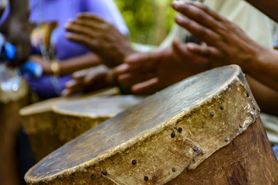 Cropped hands of people playing old drum outdoors