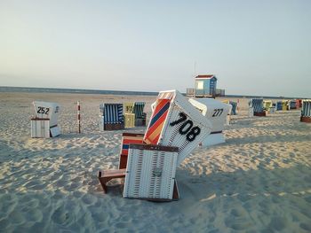 Hooded chairs on beach against clear sky