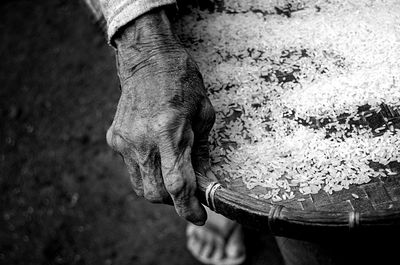 Cropped hand of person holding rice in basket