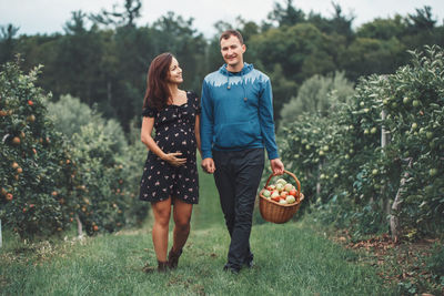 Full length of a smiling young woman standing by plants