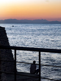 Silhouette man looking at sea against sky during sunset