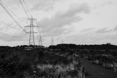 Low angle view of electricity pylon on field against sky