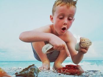 Boy sitting on beach in front of sea