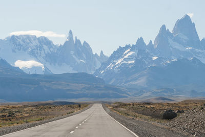 Road towards mountains against sky