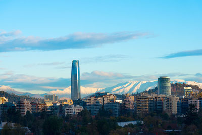 Modern buildings and mountain in city against sky