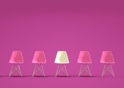 Empty chairs against pink background