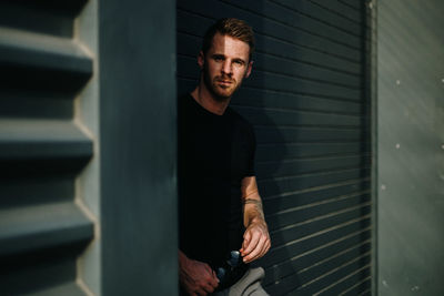 Portrait of young man standing against wall