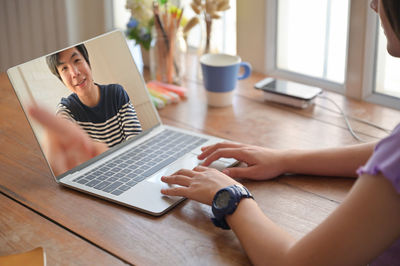 Midsection of man using mobile phone while sitting on table