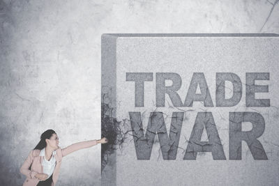 Digital composite image of businesswoman punching text on wall