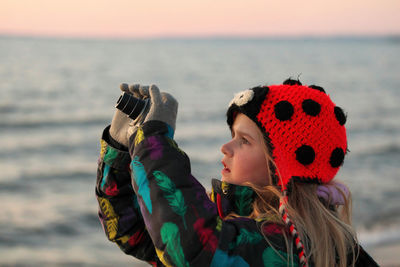 A 9 year old girl practices her photography and camera skills at the beach in the evening