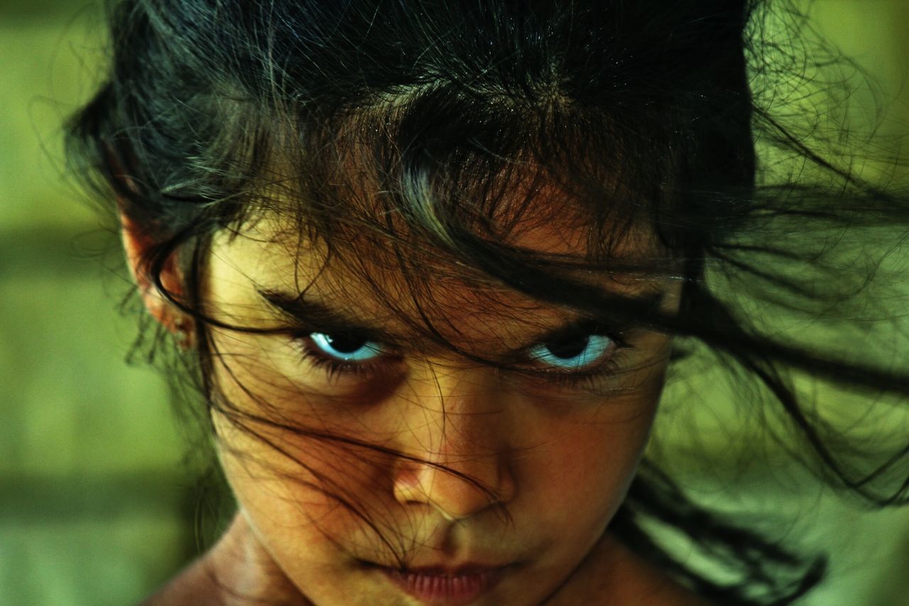 focus on foreground, headshot, close-up, lifestyles, leisure activity, human face, person, indoors, portrait, childhood, innocence, looking at camera, front view, elementary age, part of, selective focus, cute