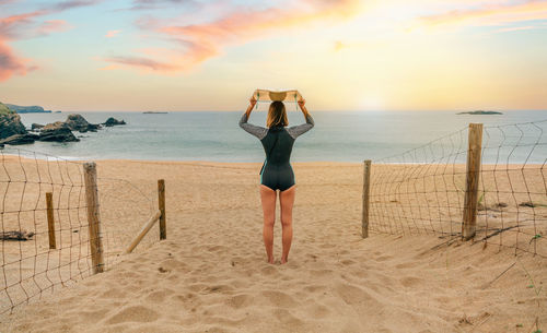 Surfer woman with surfboard on her head looking at the sea