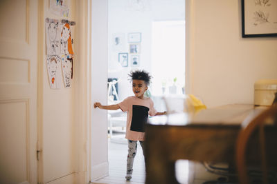 Portrait of woman standing against door at home