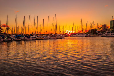 Sailboats moored on sea against sky during sunset