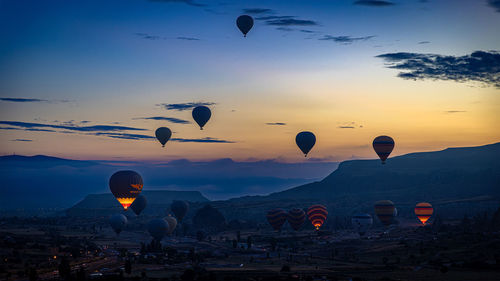 Hot air balloons flying over landscape against sky during sunset