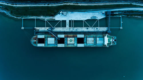 Tilt image of building by sea against blue sky