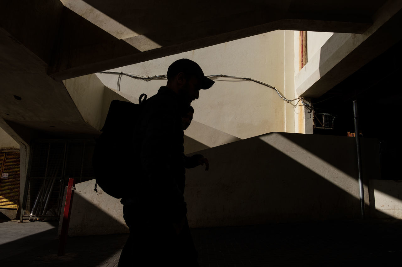 one person, indoors, architecture, standing, men, real people, built structure, three quarter length, building, lifestyles, occupation, silhouette, side view, holding, staircase, working, young adult, young men, garage