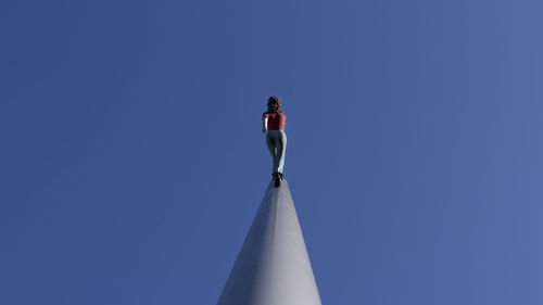 Low angle view of woman standing against blue sky