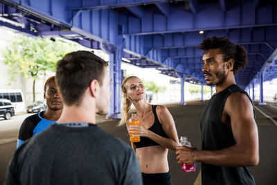 Friends drinking juices while standing on road in city