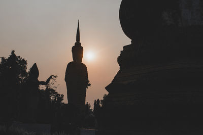 Silhouette of statue of building at sunset