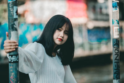 Portrait of woman standing against blurred background