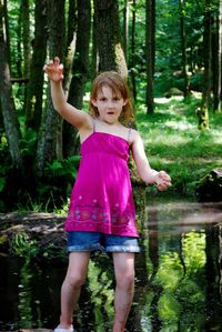 Portrait of girl standing by lake in forest