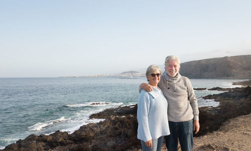 Portrait of senior couple standing against beach and sky