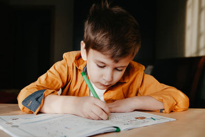 Close-up of boy drawing on book at home