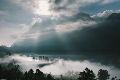 Low angle view of sunlight streaming through clouds
