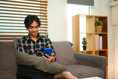 Young woman using laptop while sitting on sofa at home