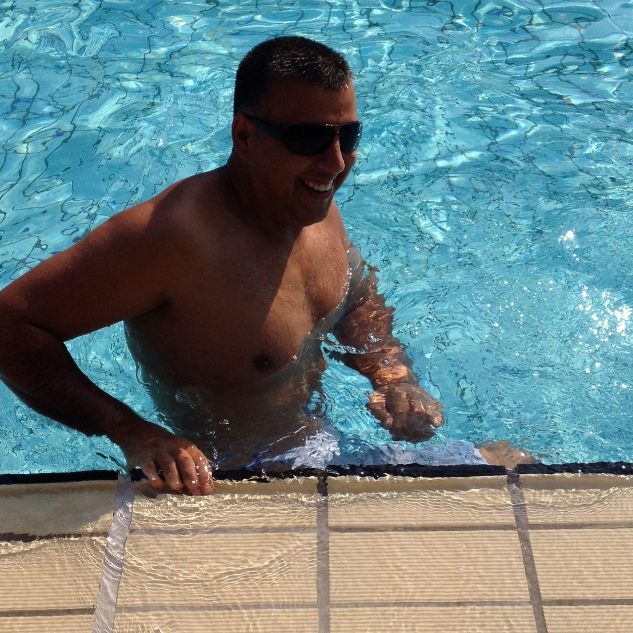 water, lifestyles, person, young adult, leisure activity, portrait, looking at camera, young men, swimming pool, shirtless, high angle view, front view, wet, relaxation, sitting, sunglasses, sea