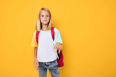 Portrait of girl standing against yellow background