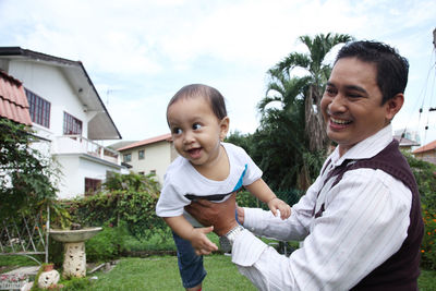 Portrait of happy mother and daughter against house