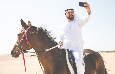 Man taking selfie while sitting on horse