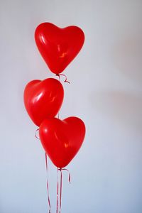 Low angle view of red balloons against white background