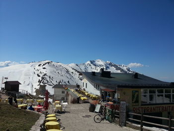 Houses on snowcapped mountain against clear blue sky