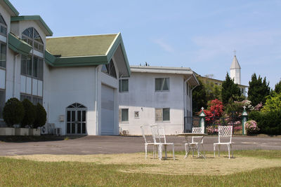 Empty chairs and tables outside building against sky