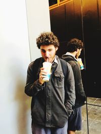 Young man looking away while holding drink