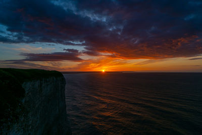 Scenic view of sea against dramatic sky during sunset