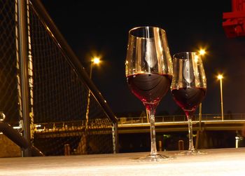 Low angle view of illuminated wine glass on railing at night