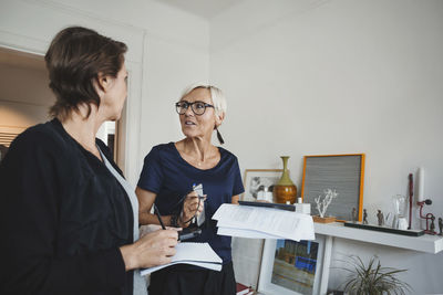 Product designers holding documents while discussing at home